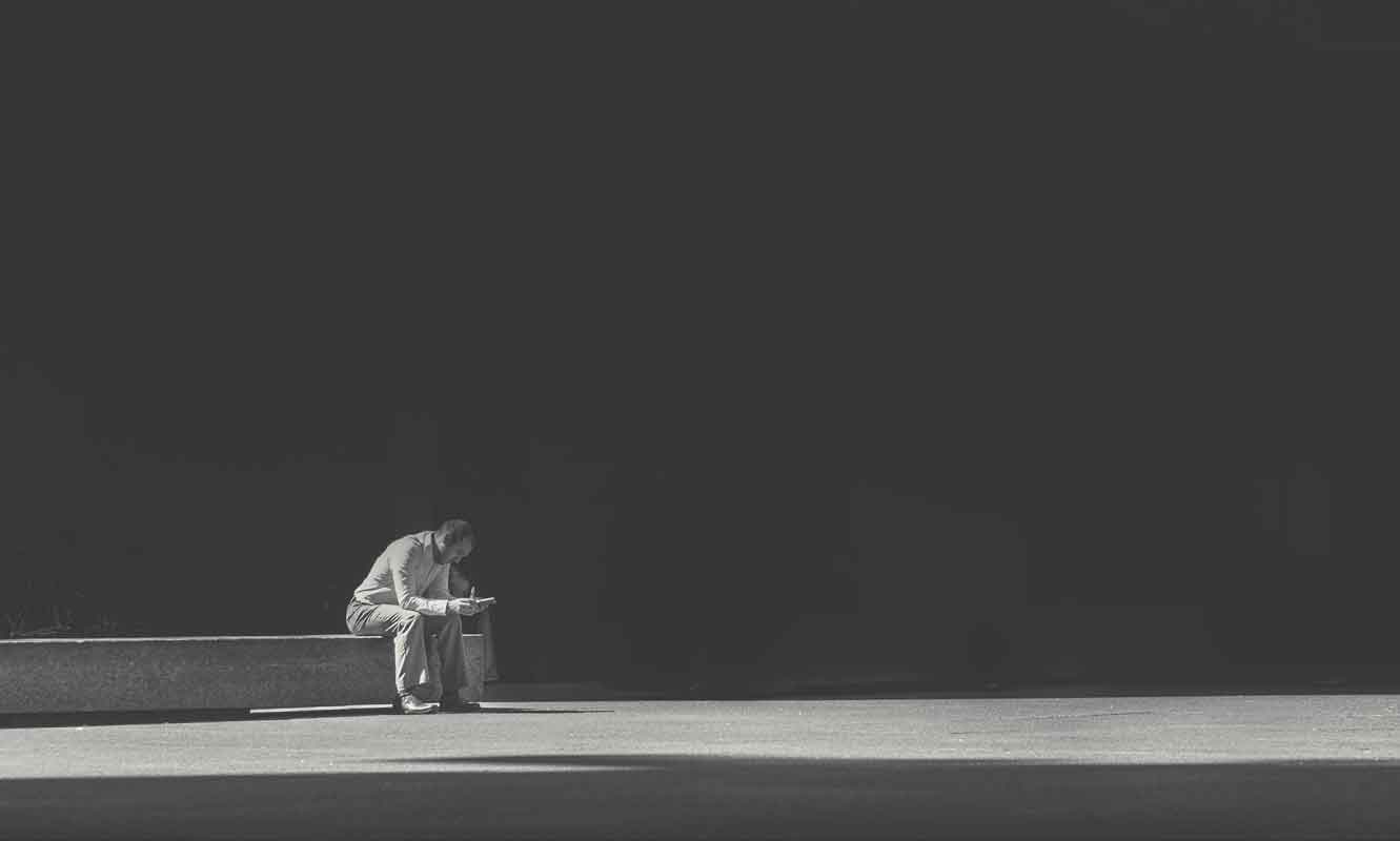 Man sitting alone on a bench, reflecting on recovery